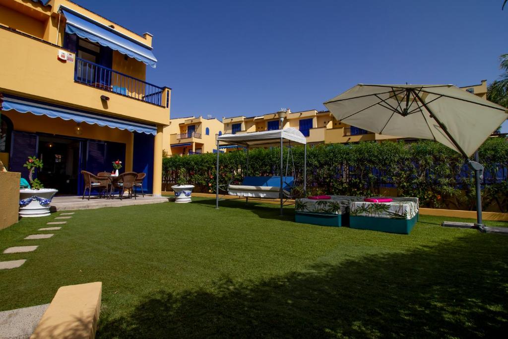 césped con sombrilla en un patio con un edificio en Sea View Meloneras Terrace Duplex +Wifi +Barbecue, en Meloneras