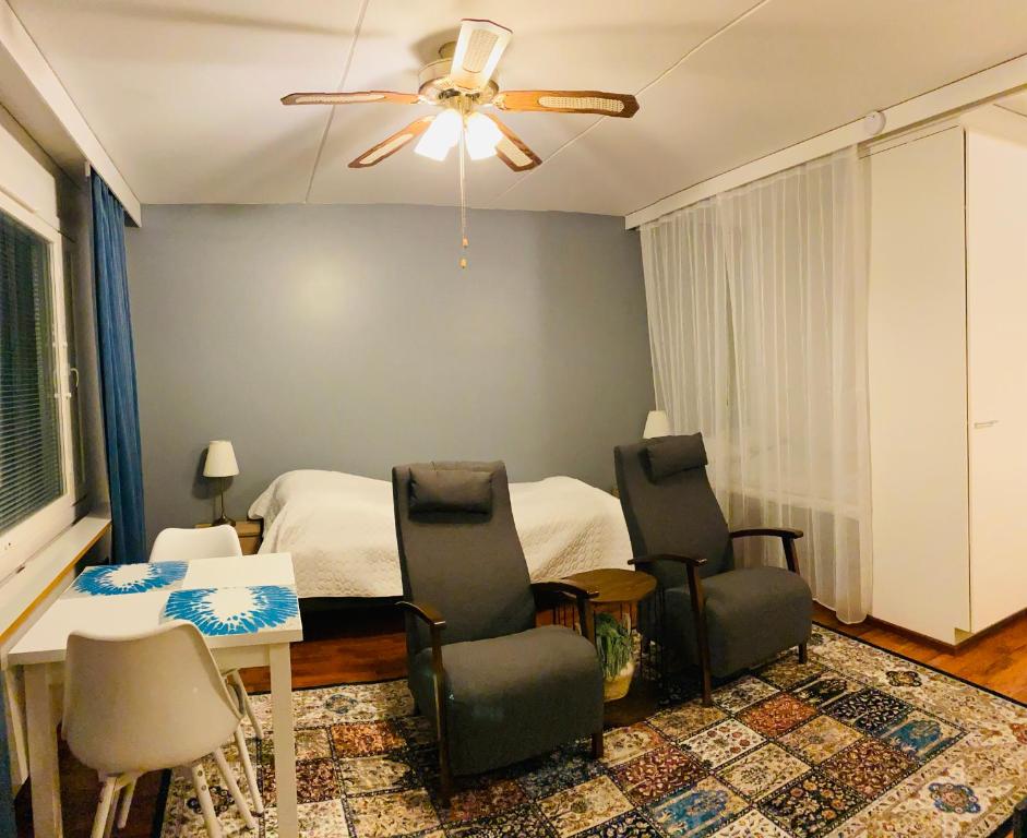 - une chambre avec un lit, des chaises et un ventilateur de plafond dans l'établissement Itäkadun Studio Apartment, à Lahti