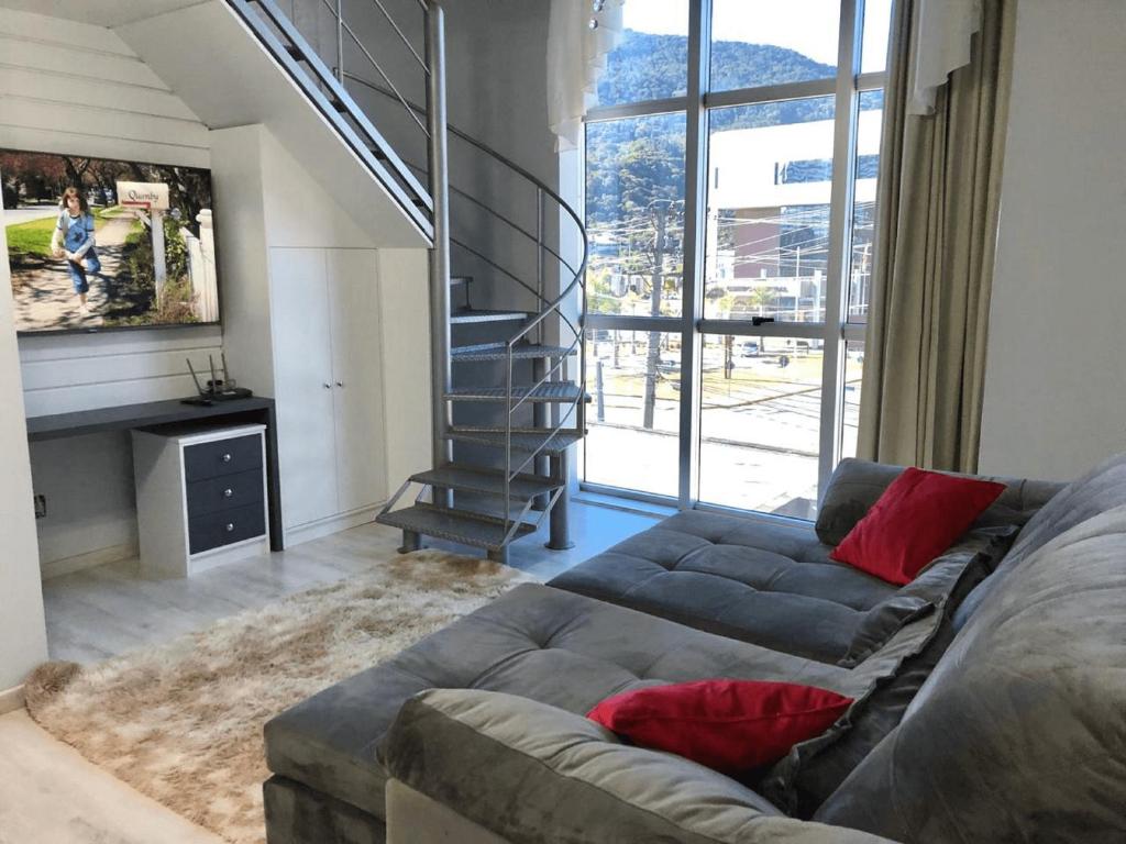 uma sala de estar com um sofá e uma escada em Saint Sebastian Flat 213 - Com Hidro! até 4 pessoas, Duplex, no centro em Jaraguá do Sul