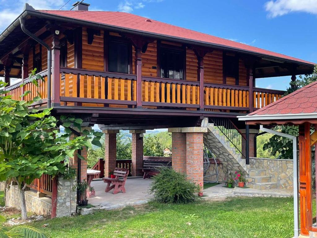 a large wooden cabin with a porch and a patio at Domacinstvo Ilici ,Gunjaci in Valjevo