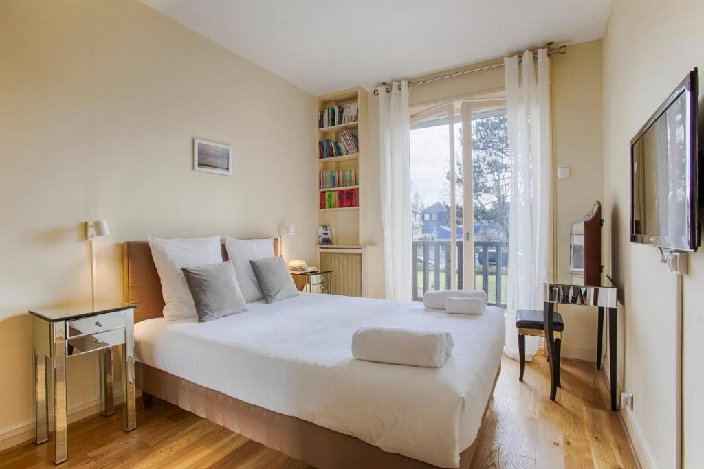 a bedroom with a large white bed and a window at La Villa Normande - One Bedroom in Deauville