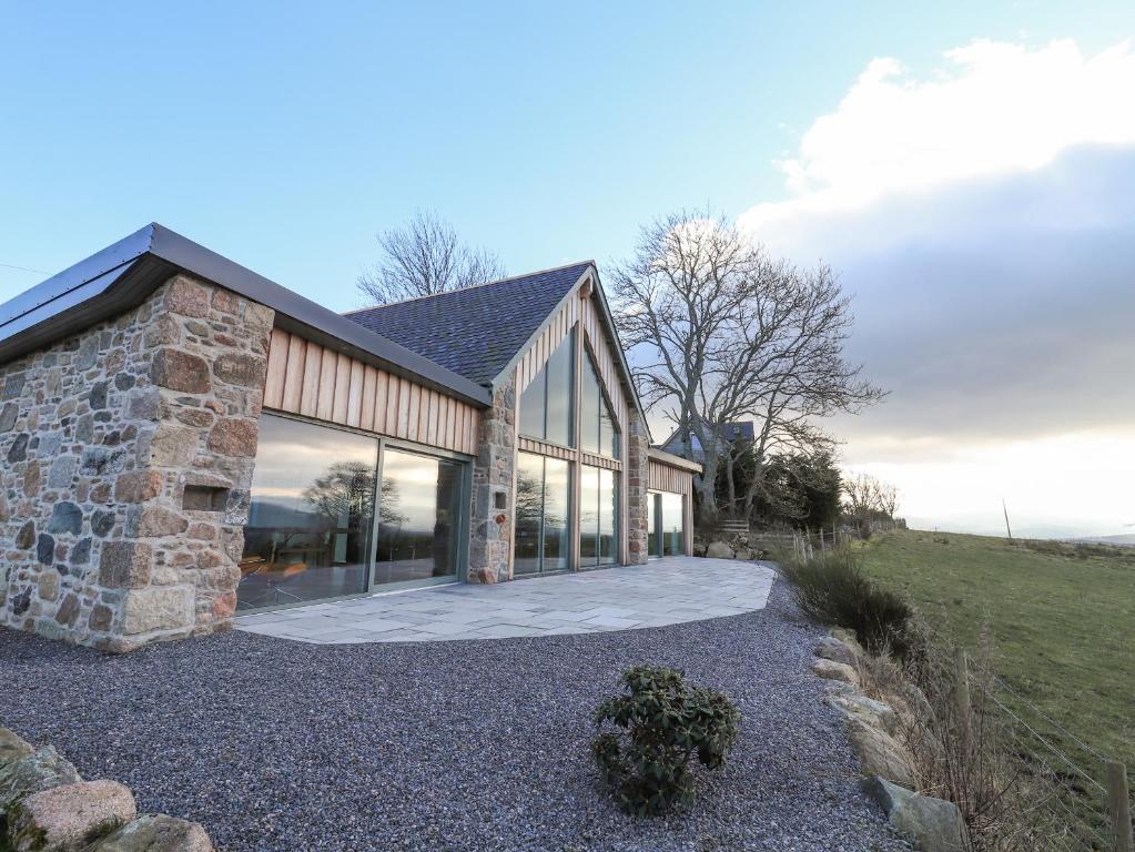 a stone house with glass windows and a driveway at Ferneytoun in Aboyne