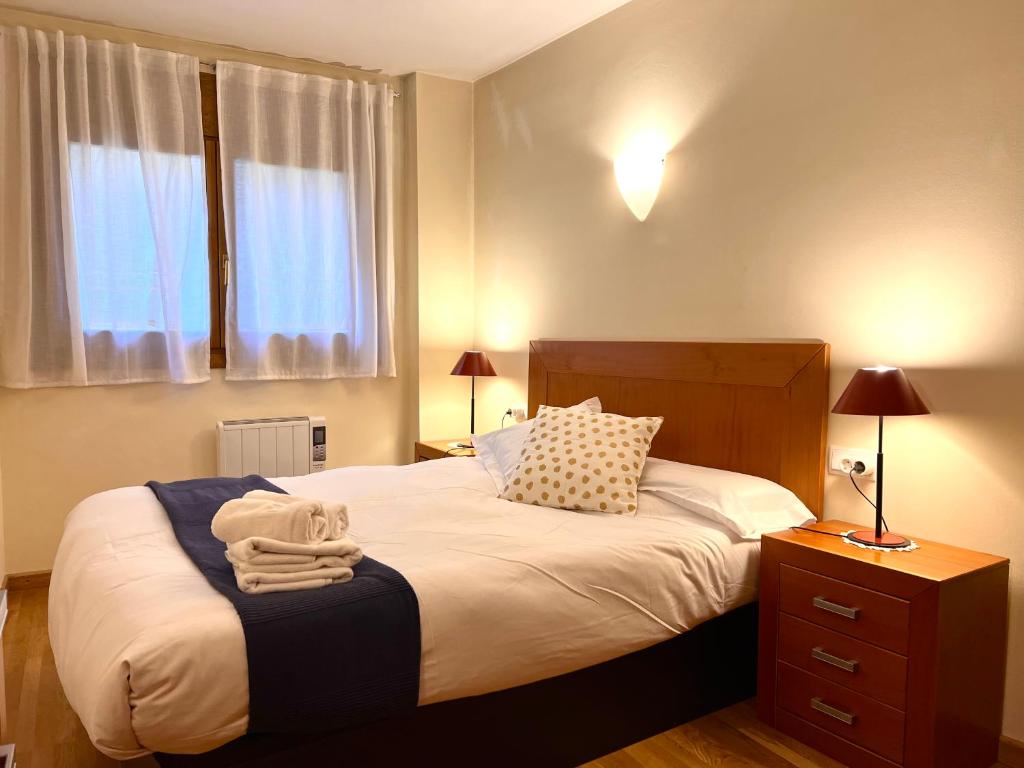 - une chambre avec un grand lit, une table de chevet et une fenêtre dans l'établissement Apartament Boet - Ainet de Cardós, à Vall de Cardos