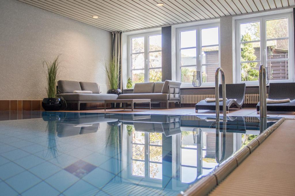 uma grande piscina com sofás e cadeiras em Boutique-Hotel Weigels Bergfreiheit em Winterberg