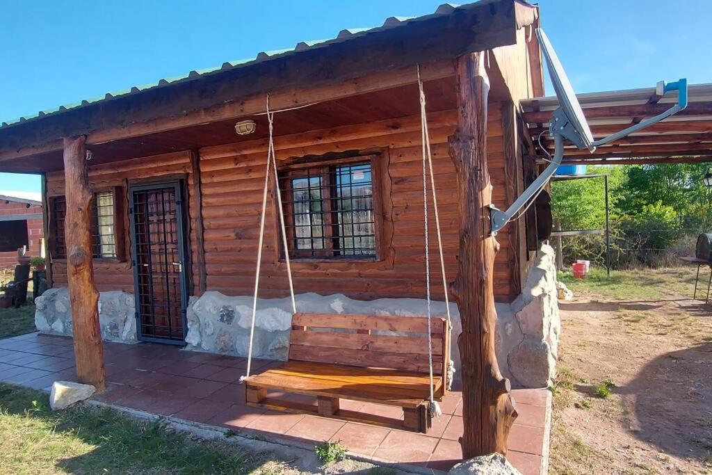 a log cabin with a porch swing at CABAÑA AKAPANA in Huerta Grande