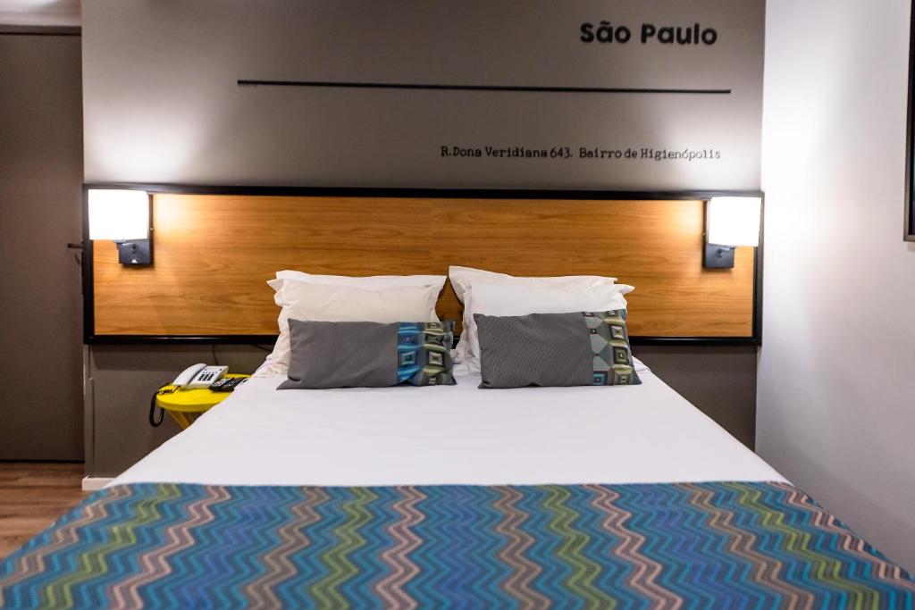 uma cama grande com duas almofadas num quarto em Monreale Lifestyle Higienópolis São Paulo em São Paulo