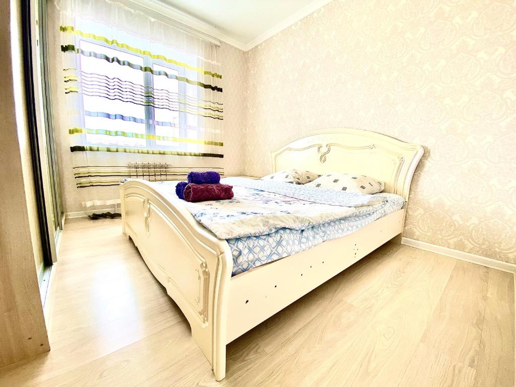 ein kleines Schlafzimmer mit einem weißen Bett in einem Zimmer in der Unterkunft Апартаменты 2 комнатная в новом ЖК in Aqtöbe