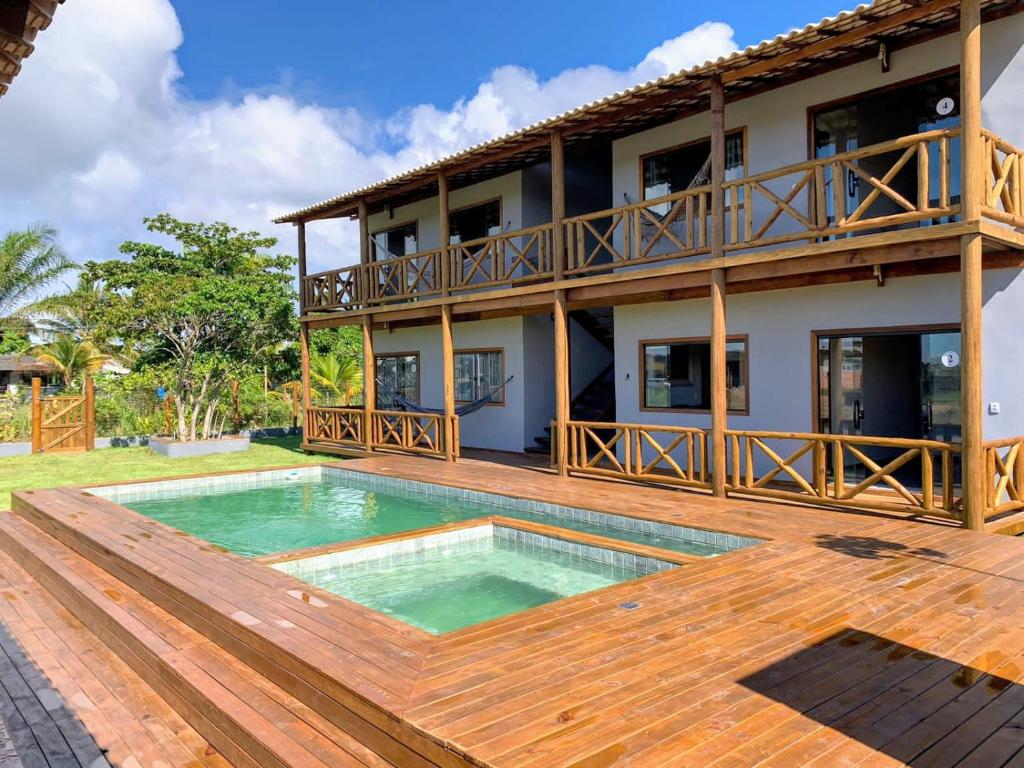 uma casa com uma piscina e um deque de madeira em Via Del Mare Flats em Maraú