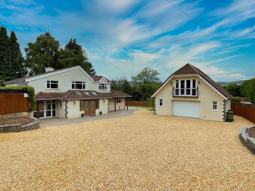 a white house with a garage on a gravel driveway at Big House in countryside near Cardiff in Rudry