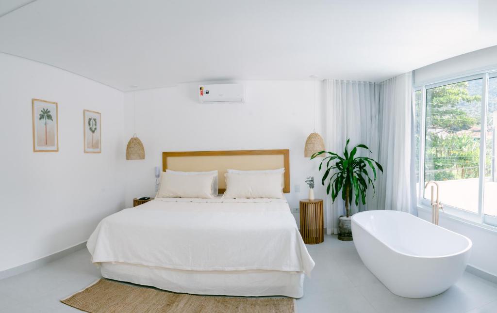 um quarto branco com uma cama grande e uma banheira em Olisa Hotel Boutique em Maresias