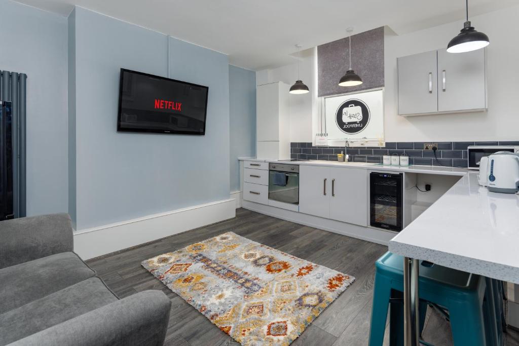 a kitchen with white cabinets and a tv on the wall at Snuggle Cove Apartments By Snazzy Short stay in Liverpool