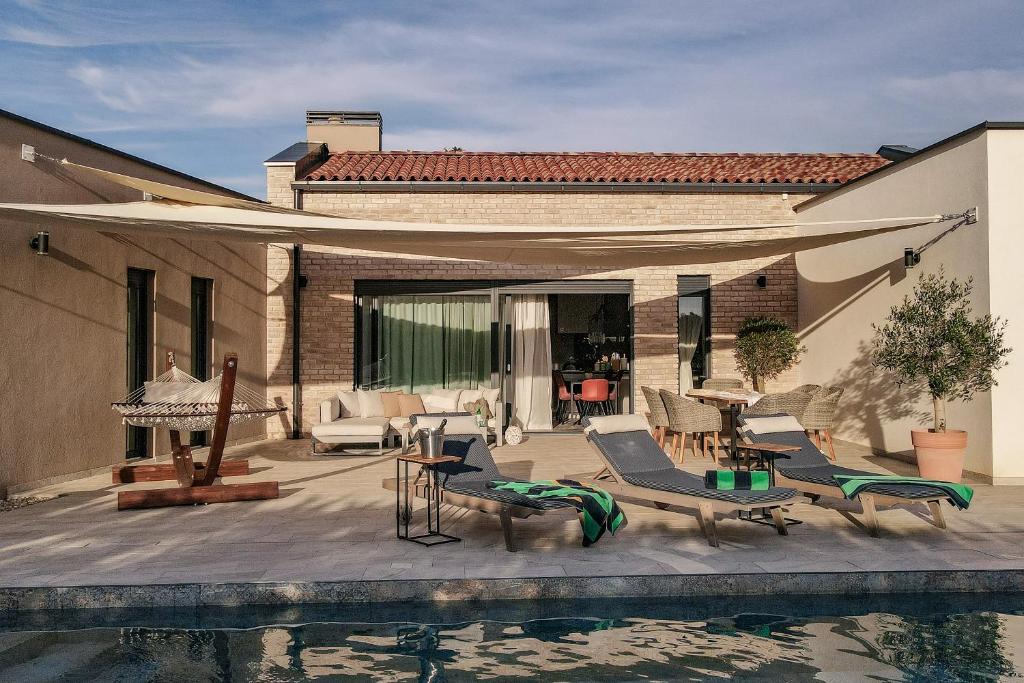 a patio with chairs and a pool in front of a house at Villa Arya in Juršići