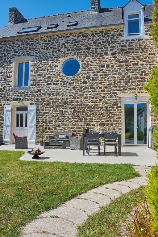 une maison en briques avec une table et des bancs devant elle dans l'établissement Home Emoi, à La Gouesnière