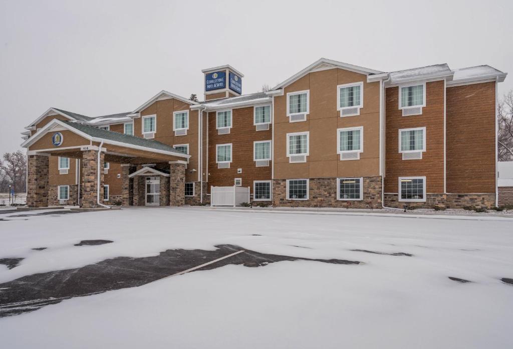 un edificio con un estacionamiento en la nieve en Cobblestone Hotel & Suites - Hutchinson, en Hutchinson