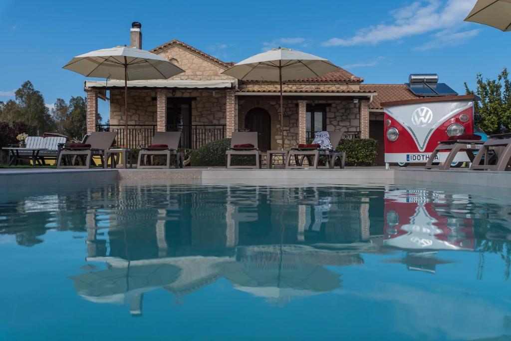 a house with a swimming pool and umbrellas at Idothea Stone Villa in Kalpaki