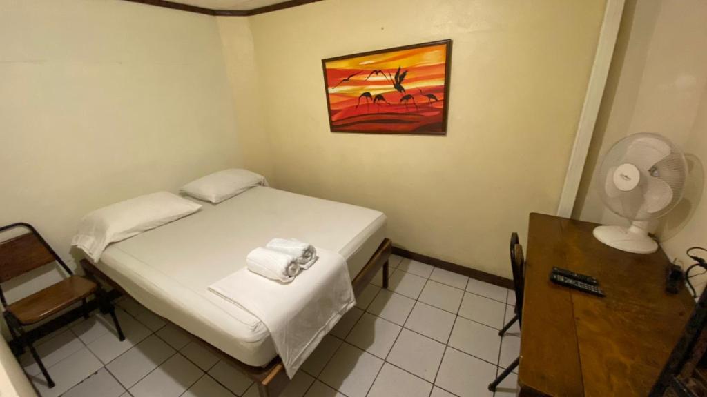 a small bedroom with a bed and a fan at Hostel Pura Vida en Liberia in Liberia
