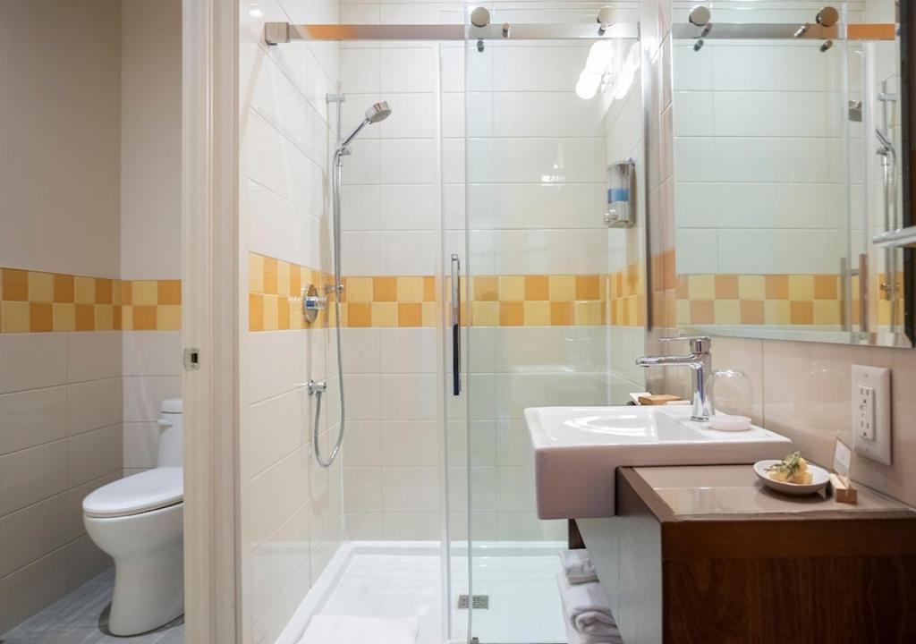 a bathroom with a shower and a sink and a toilet at Hotel Mont-Tremblant in Mont-Tremblant