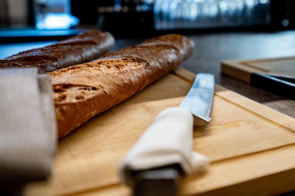 two loaves of bread on a cutting board with a knife at Hotel Jacobs in Bruges