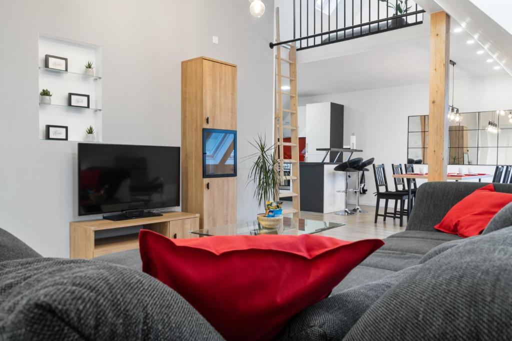 a living room with a gray couch with red pillows at Modernes 3-Zimmer Loft Eslohe Hennesee 5 min in Eslohe