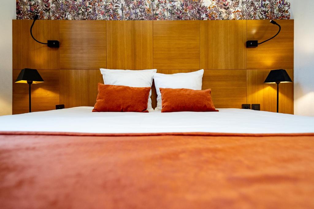 a bedroom with a large bed with two orange pillows at Hotel Jacobs in Bruges