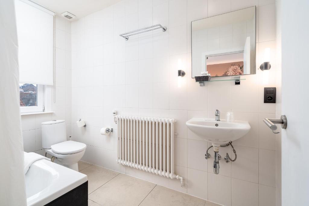 a white bathroom with a sink and a toilet at Hotel Jacobs in Bruges