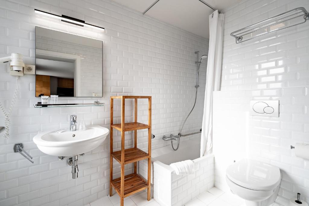 a bathroom with a sink and a toilet and a mirror at Hotel Jacobs in Bruges