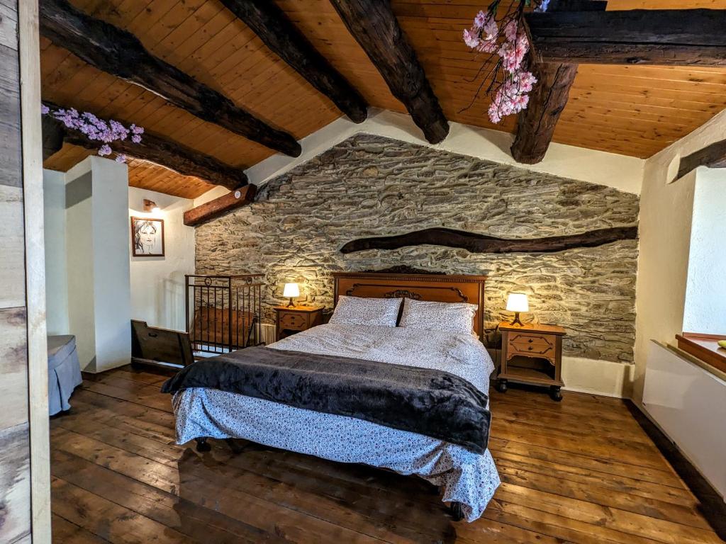 a bedroom with a bed and a stone wall at Casa Nenella in Paesana