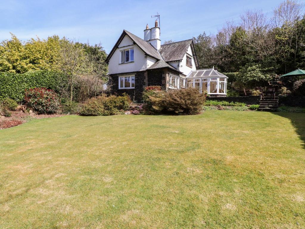 a house with a large lawn in front of it at Brunton Lodge in Bowness-on-Windermere