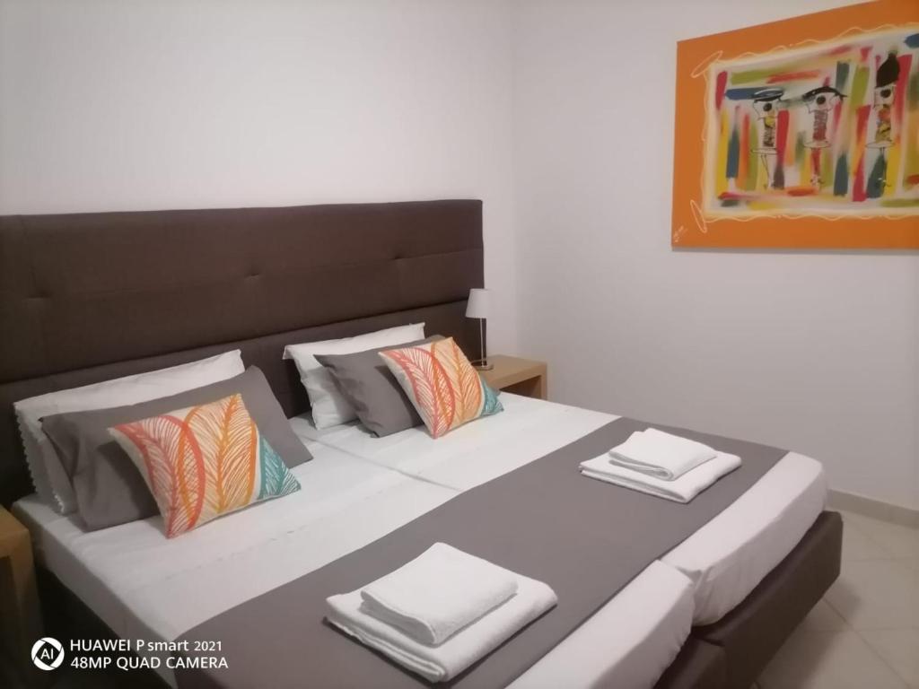 um quarto com uma cama grande com lençóis brancos e almofadas em Solaren Apartments Boavista em Sal Rei