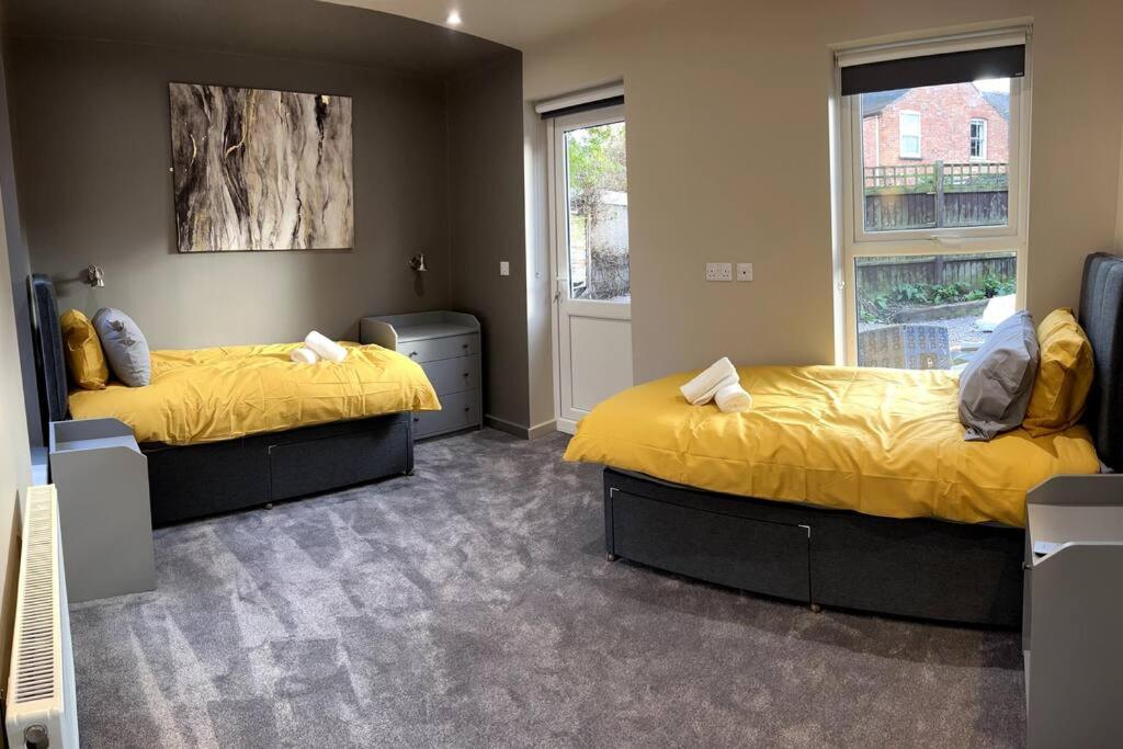 1 dormitorio con 2 camas con sábanas amarillas y ventana en University Apartment • Sleeps 8 en Loughborough