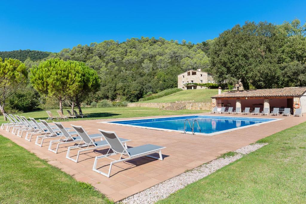 a row of lounge chairs next to a swimming pool at B&B Can Jan in Sant Ferriol