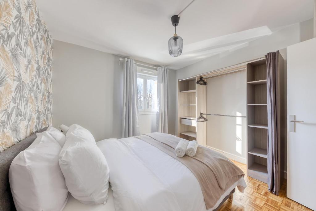 a bedroom with a white bed with white pillows at Spacieux 3 pièces Paris / Disney in Noisy-le-Grand