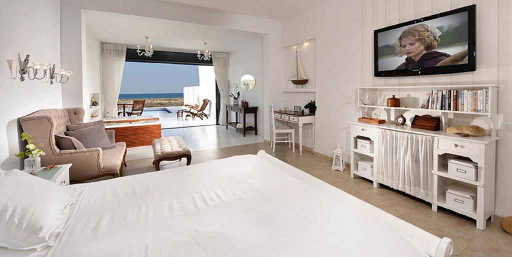 a white bedroom with a bed and a living room at Yamim Suites On The Beach in Shave Ẕiyyon