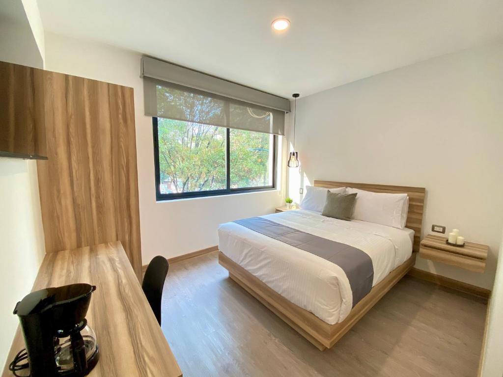 1 dormitorio con cama, mesa y ventana en Darwin 8, en Ciudad de México