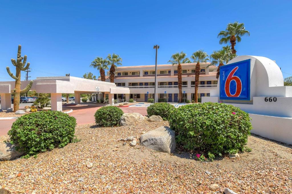 a hotel with a sign and bushes in front of a building at Motel 6-Palm Springs, CA - Downtown in Palm Springs