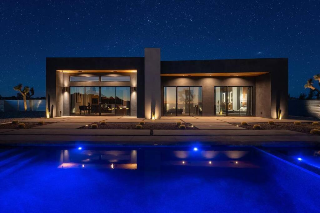 - un bâtiment avec une piscine en face de lui la nuit dans l'établissement Mountain View Paradise -POOL & SPA, à Yucca Valley
