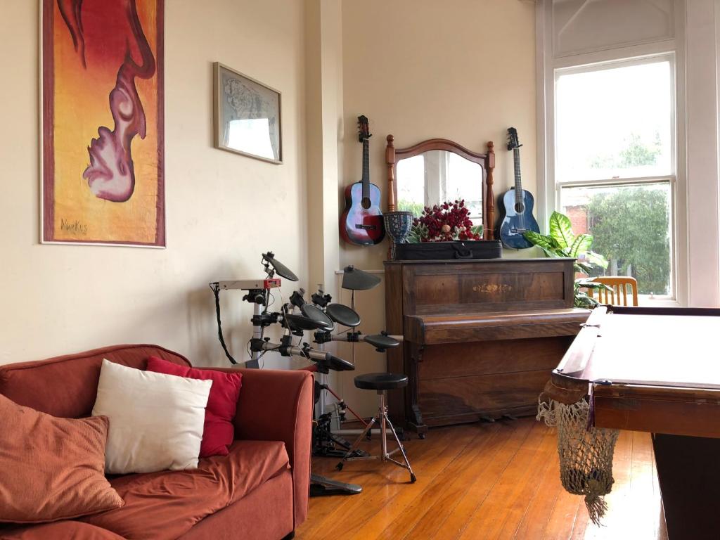 a living room with a couch and a piano at Chalet Backpackers in Dunedin