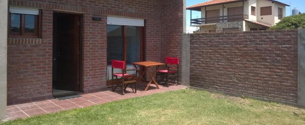 un patio con mesa y sillas en una pared de ladrillo en Apartamento Lastres 27 en Santa Clara del Mar