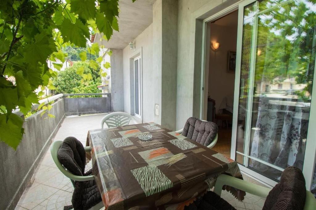 a table and chairs on a balcony with a table and a glass door at Apartment Sanja in Rab