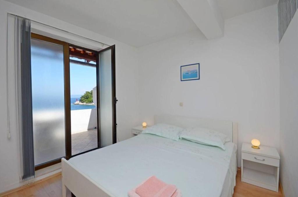 a bedroom with a white bed and a large window at Apartments and Rooms Barbara in Lastovo