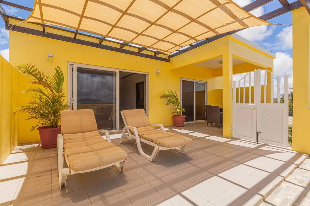 South Hill Village的住宿－The Junior Suite's "Palm Studio Apartment"，一个带两把椅子的庭院和黄色的房子