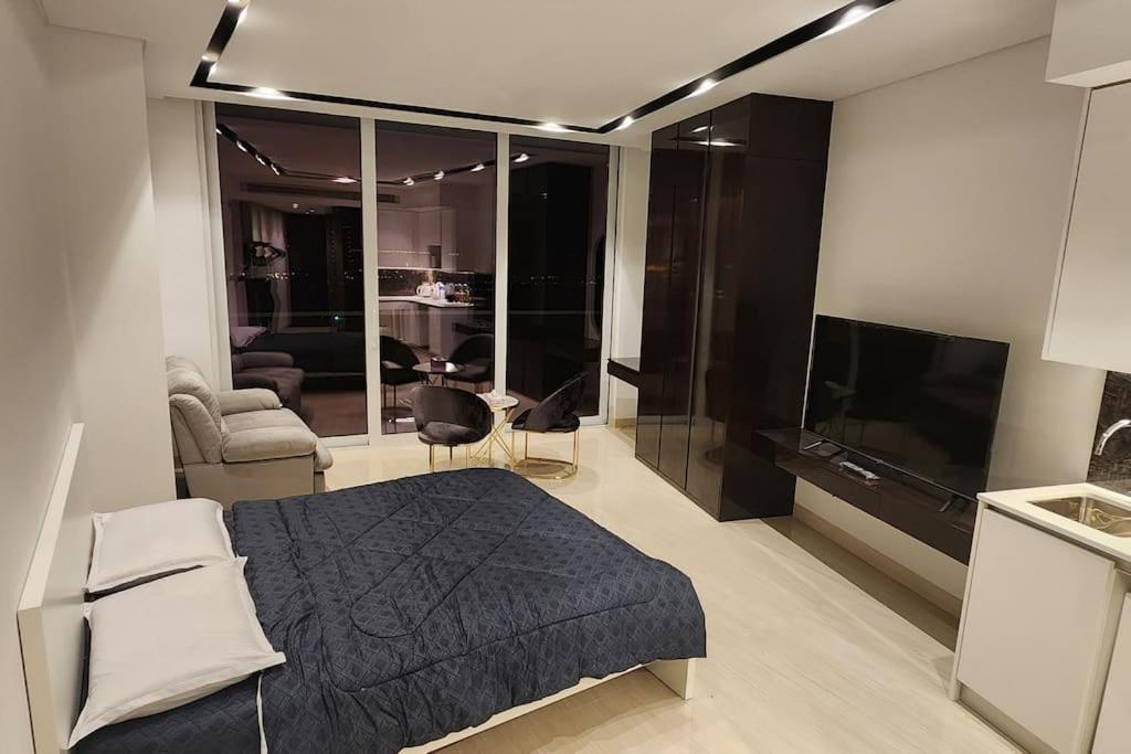 studio apartment with balcony في Seef: غرفة نوم بسرير واريكة وتلفزيون