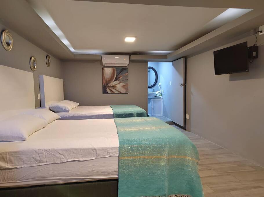 a bedroom with two beds and a flat screen tv at 10th ave Suite in Cozumel