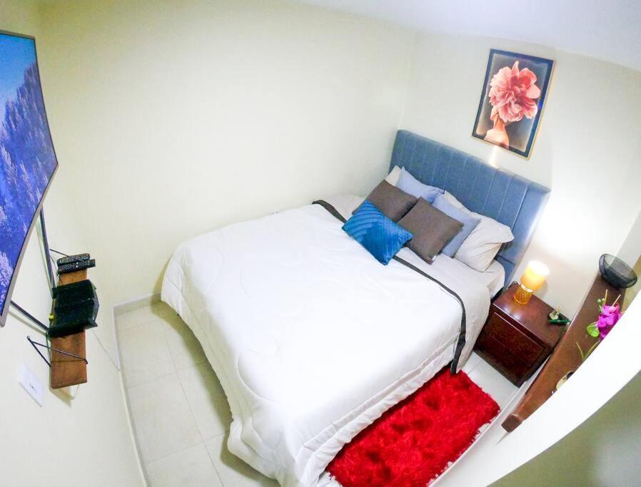 1 dormitorio con 1 cama blanca grande con manta roja en Apartamento en Suba, Bogotá, en Bogotá