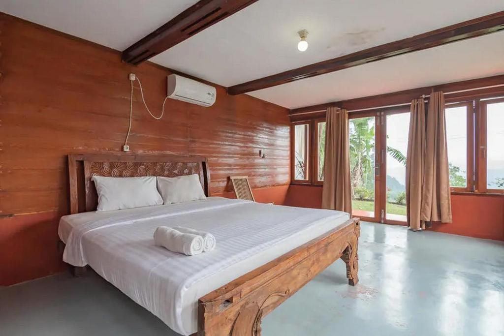 a bedroom with a large bed with a wooden wall at Kanaka Residence Mitra RedDoorz in Bandungan