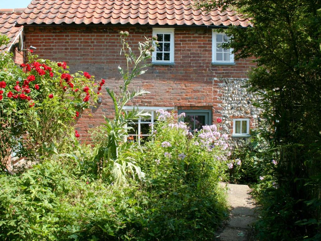 a brick house with flowers in front of it at Pear Tree Cottage in Wenhaston