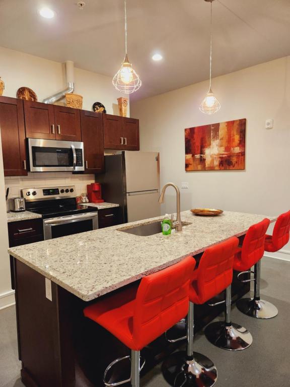 a kitchen with a counter with a sink and red bar stools at Modern studio, Heart of Riverside Sq. mins shops. in East Providence