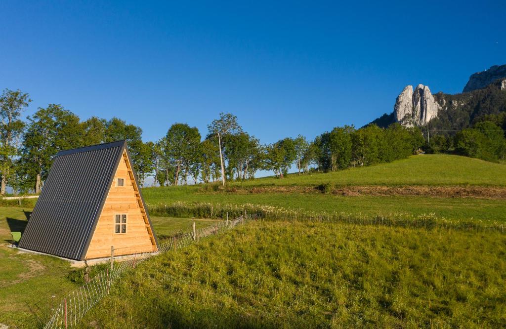 a small house in a field with a mountain in the background at Ferme Rony Camp des Découvreurs in Saint-Nizier-du-Moucherotte