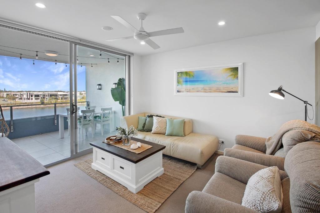 a living room with a couch and a table at Pool, 100m to Hosp, 3 TVs, 3 Beds - Lakefront Aquarius Apartment in Kawana Waters