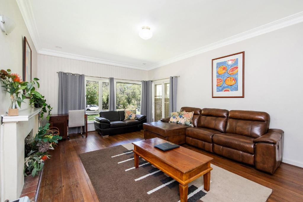 a living room with a leather couch and a table at Busselton River Cottage with WiFi in Busselton
